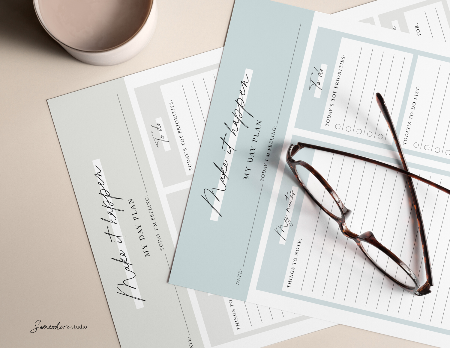 2 printed day notes sitting on a table with a pair of glasses