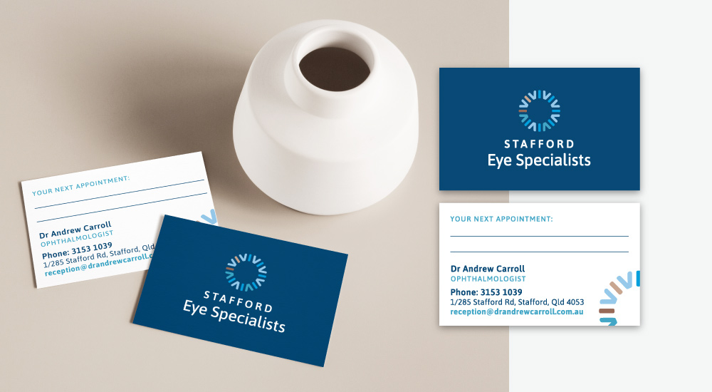 Front and back of new business cards, sitting on a table with vase