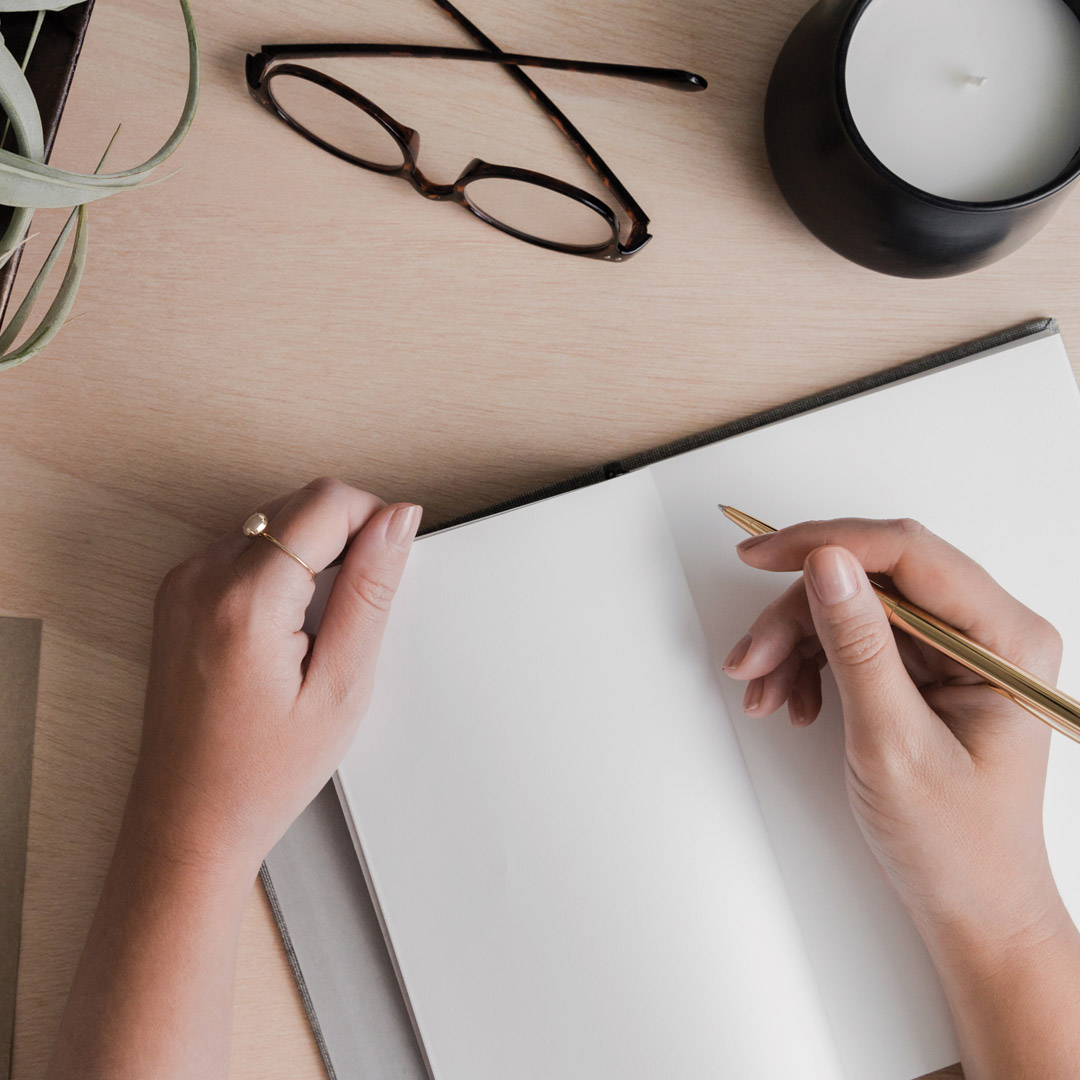 Image of woman drawing graphic design elements on a notebook.